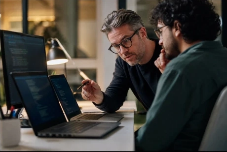 Persona aportando refuerzo técnico frente a un monitor con código.